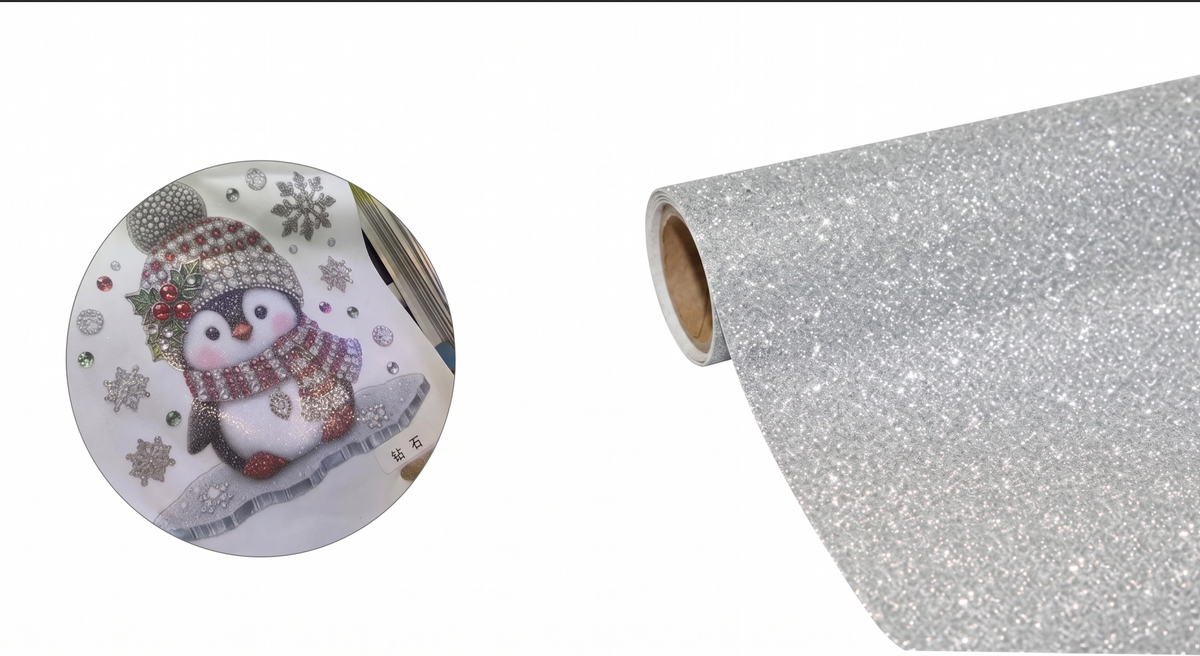 Silver glitter diamond DTF transfer film roll alongside a printed sample featuring a sparkling winter penguin design to show actual crystal shimmer effect